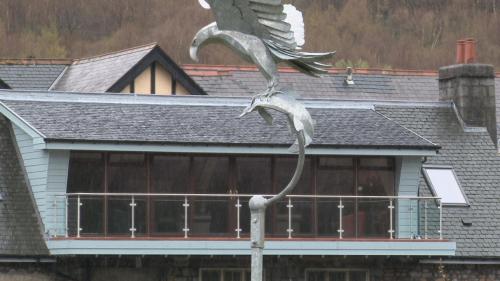 a statue of a bird on a pole in front of a house at Highland Getaway in Kinlochleven