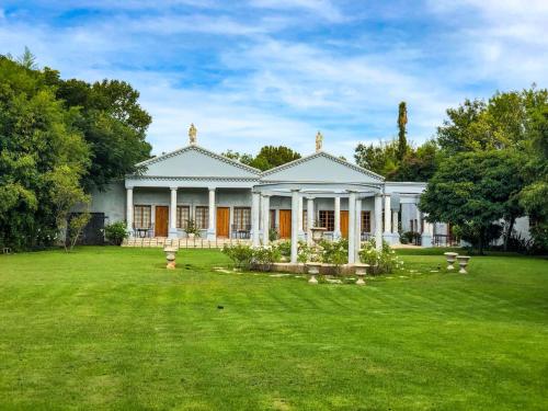a large white house with a large yard at Ancient Emperor Guest Estate in Potchefstroom