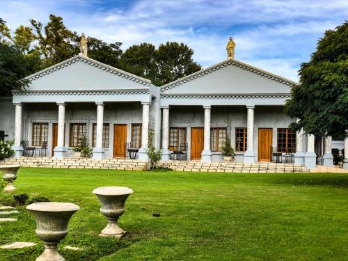 a large white building with a statue in the yard at Ancient Emperor Guest Estate in Potchefstroom