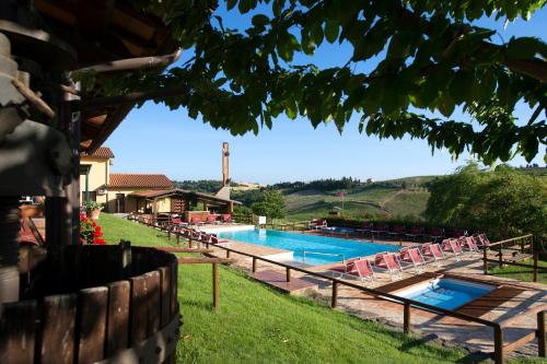 a swimming pool in a yard with chairs around it at Borgo Filicardo in Montespertoli