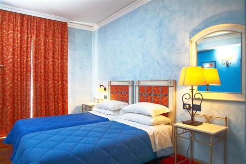 Hotel Nautico Pozzallo في بوزالو: غرفة نوم بسرير ازرق وستائر حمراء