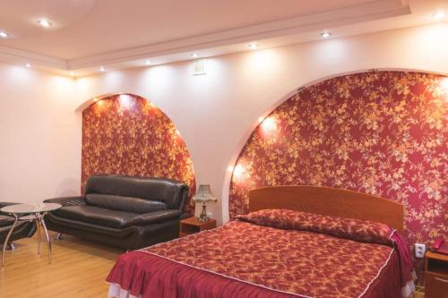 Triumph Hotel في Rudny: غرفة نوم بسرير وكرسي جلدي