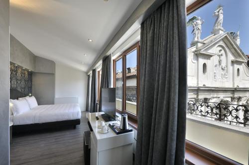 a hotel room with a bed and a large window at Al Theatro Palace in Venice