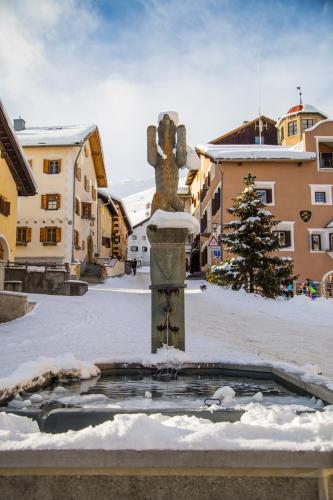 a statue of a cross in a courtyard with snow at Hotel Klarer in Zuoz