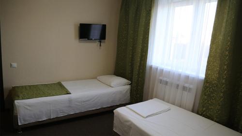 KotlyakovoにあるSky Village Guest Houseのベッド2台、テレビ、窓が備わる客室です。