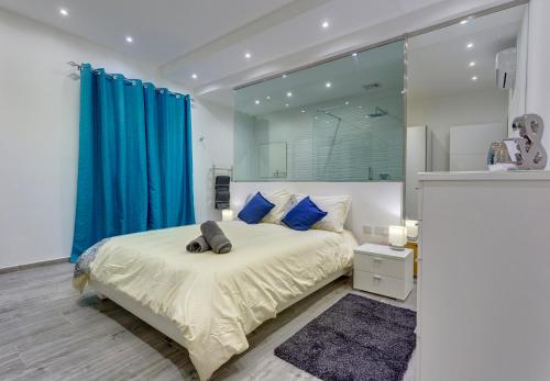 a bedroom with a bed with blue curtains and a mirror at Luxury 3BR Apartment with Marina Views in Il-Gżira