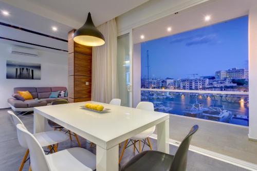 a dining room with a white table and chairs and a large window at Luxury 3BR Apartment with Marina Views in Il-Gżira