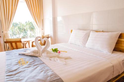 two white swans sitting on top of a bed at Mui Ne Beach Hotel in Mui Ne