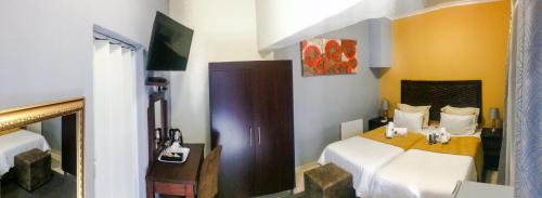 een kleine slaapkamer met 2 bedden en een televisie bij Ehrlichpark Lodge self catering and spa in Bloemfontein