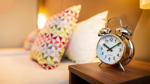 an alarm clock sitting on a table next to a bed at Campanile Hotel & Restaurant Amsterdam Zuid-Oost in Amsterdam