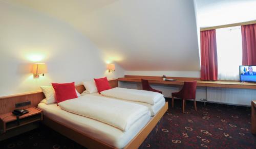 a hotel room with a bed and a desk at Hotel Vierjahreszeiten in Breitengüßbach