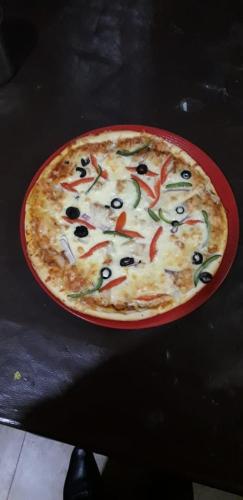 a pizza in a red plate on a table at Hotel Royal Gardens Lahore in Lahore