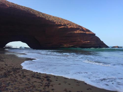 a beach with a large rock in the water at HOTEL BEACH CLUB LEGZIRA in Sidi Ifni
