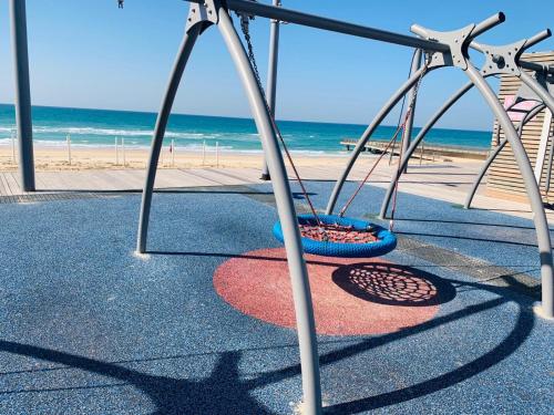 a swing set with the beach in the background at Motel Hofim in Bat Yam