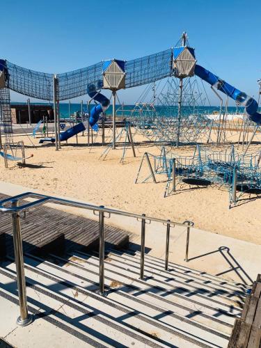 a playground on the beach with a slide at Motel Hofim in Bat Yam