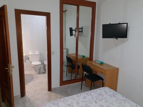 1 dormitorio con cama, escritorio y espejo en Hostal Angelines, en Madrid