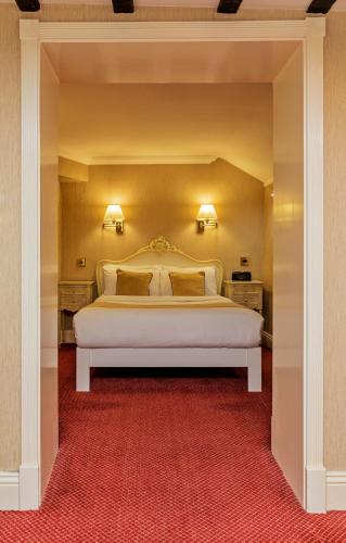 a bedroom with a large white bed with a red carpet at Rogerthorpe Manor Hotel in Pontefract