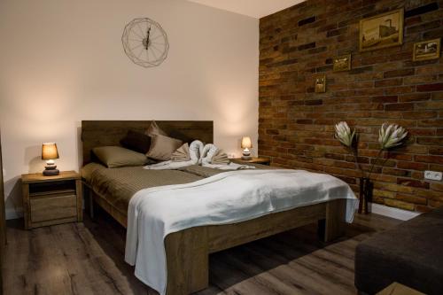 a bedroom with a bed and a brick wall at Liget Apartman in Gyula