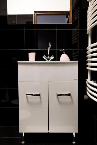 a white sink in a bathroom with a black wall at Liget Apartman in Gyula