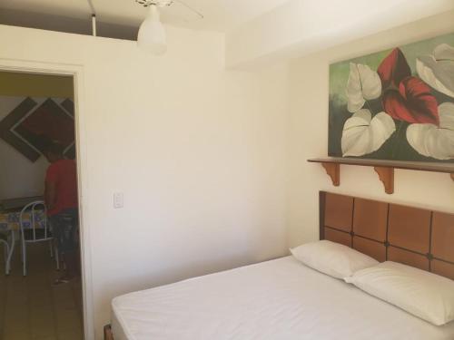 a bed in a room with a painting on the wall at Kitnet em Guarapari in Guarapari