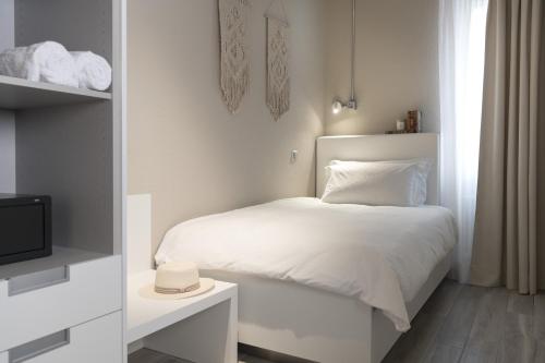 a white bedroom with a bed and a tv at CP Resort in Taverne