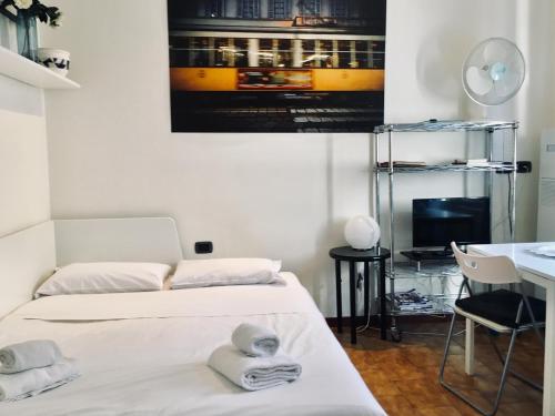 ミラノにあるCozy Central Studio - Porta Romanaのベッドルーム1室(ベッド2台付)が備わります。壁には絵画が飾られています。