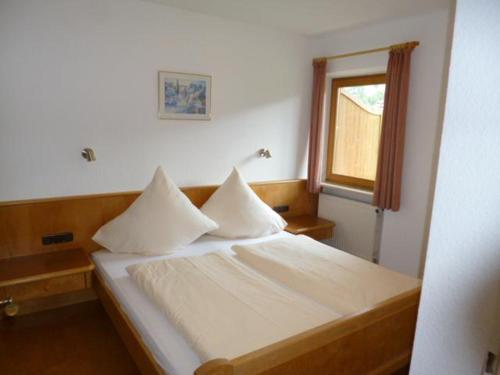 a bedroom with a bed with white sheets and a window at Haus Marianne in Oberjoch