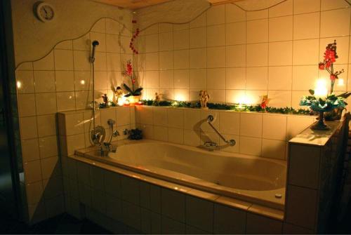 a bath tub in a tiled bathroom with lights at Ferienhof Ammann in Bad Hindelang