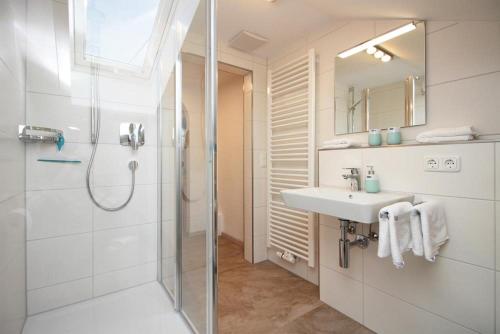 a white bathroom with a shower and a sink at Ferienwohnung Pinocchio in Bad Hindelang