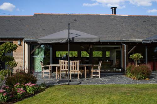 un patio avec une table, des chaises et un parasol dans l'établissement La Maison des Vignes - Domaine de la Soucherie, à Beaulieu-sur-Layon