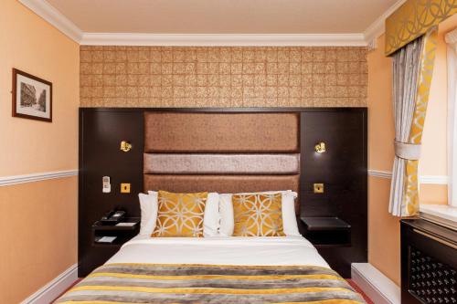 a bedroom with a large bed with a large headboard at Rogerthorpe Manor Hotel in Pontefract