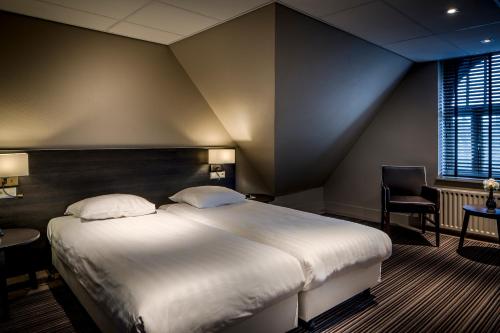 a bedroom with a large bed and a chair at Fletcher Hotel Restaurant Boschoord in Oisterwijk