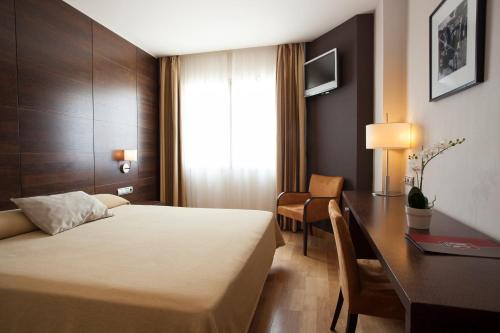 a hotel room with a bed and a desk at Hotel FC Villalba in Collado-Villalba
