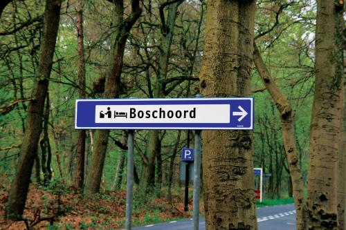 a blue and white street sign next to a tree at Fletcher Hotel Restaurant Boschoord in Oisterwijk