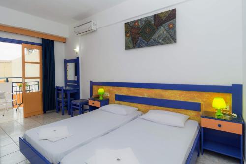 a bedroom with a large white bed with a blue headboard at Eltina Apartments in Malia