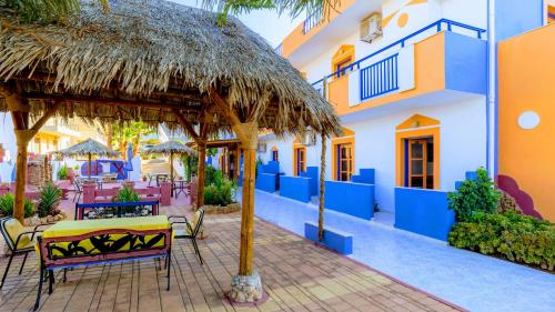 a patio with a table and chairs and a straw umbrella at Eltina Apartments in Malia