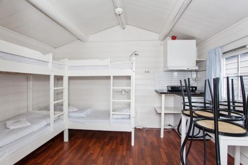 Habitación con literas blancas, mesa y sillas. en Midttun Motell & Camping AS, en Bergen