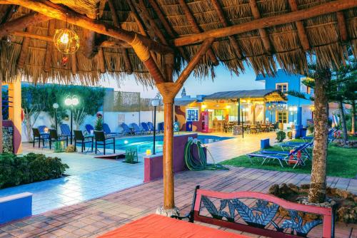 a resort with a pool and tables and chairs at Eltina Apartments in Malia