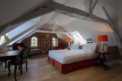 a bedroom with a bed and a desk in a attic at La Maison des Vignes - Domaine de la Soucherie in Beaulieu-sur-Layon