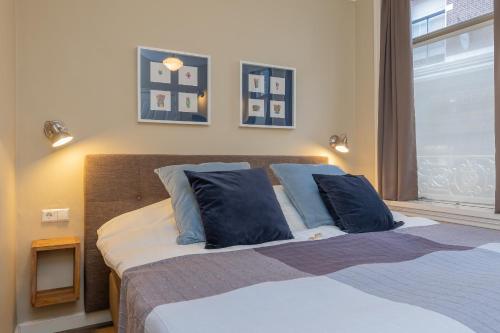 a bedroom with a bed with blue pillows and a window at ExLibris Boutique Hotel in Leiden