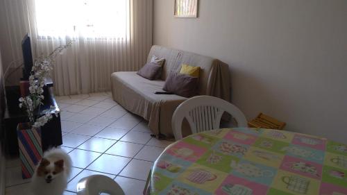 Habitación con mesa, sofá y perro en Ótimo apto de temporada em BC, en Balneário Camboriú