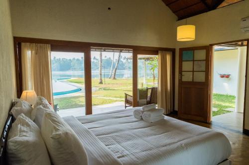 a bedroom with a large bed with a large window at Cranganor History Café & Riverside Château in Parūr