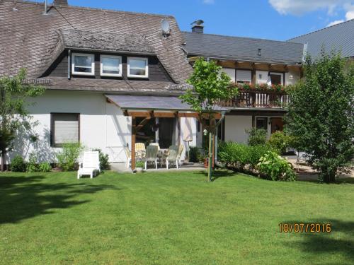 a house with a yard with chairs and a balcony at Ferienwohnungen Grafenfelder Hof in Gerolstein