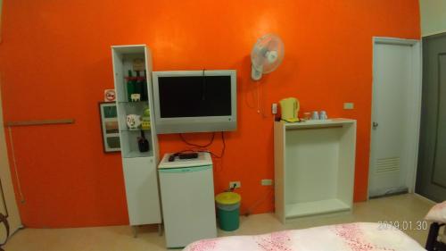 a room with an orange wall with a tv on a wall at 悦來民宿 台東縣民宿334號 in Taiping