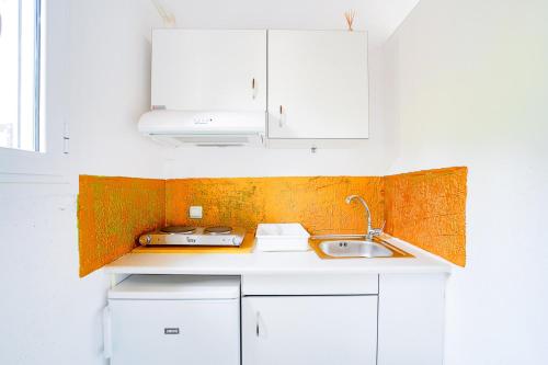 una cocina con armarios blancos y fregadero en Art Studio Kefalonia, en Dhavgáta