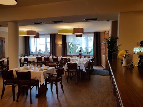 une salle à manger avec des tables blanches, des chaises et des fenêtres dans l'établissement Gasthof Zur Friedenseiche, à Lohsa