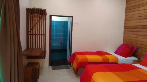 a room with two beds with colorful sheets at Naura Roomstay in Kuala Tahan