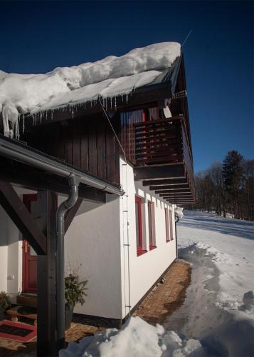 a house with snow on top of it in the snow at Apartmány Fišerka in Rokytnice nad Jizerou