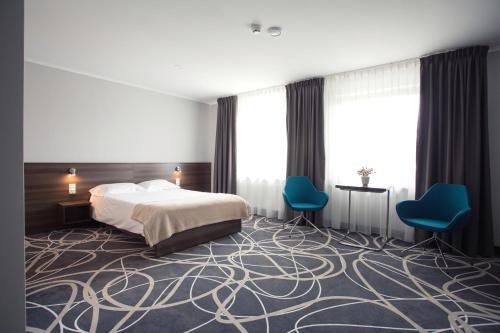 pokój hotelowy z łóżkiem i 2 niebieskimi krzesłami w obiekcie Hotel Nad Nettą w mieście Augustów