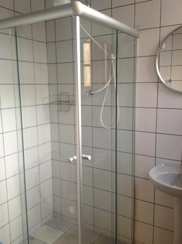 a shower with a glass door next to a sink at Pousada Telhado Azul in Abraão